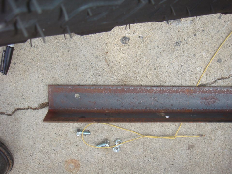 Tire tread above a rusty metal bracket with bolts and nuts on concrete