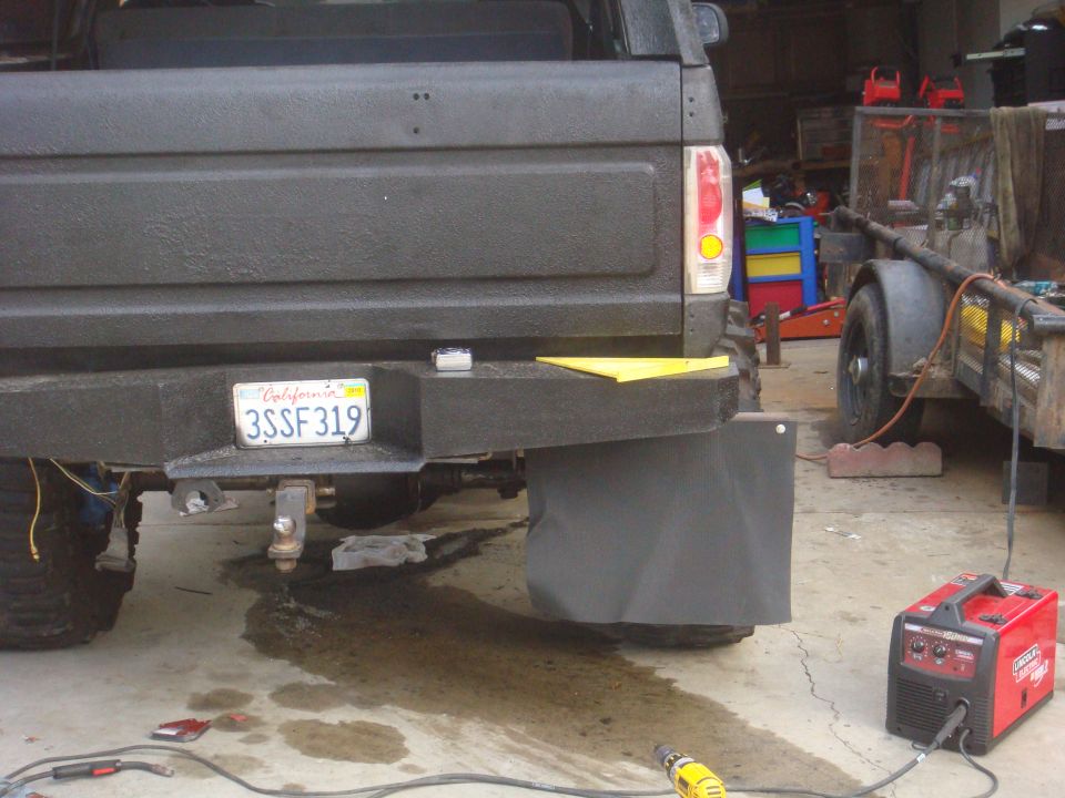Black pickup truck rear with custom bumper, mud flaps, and California license plate 3SSF319