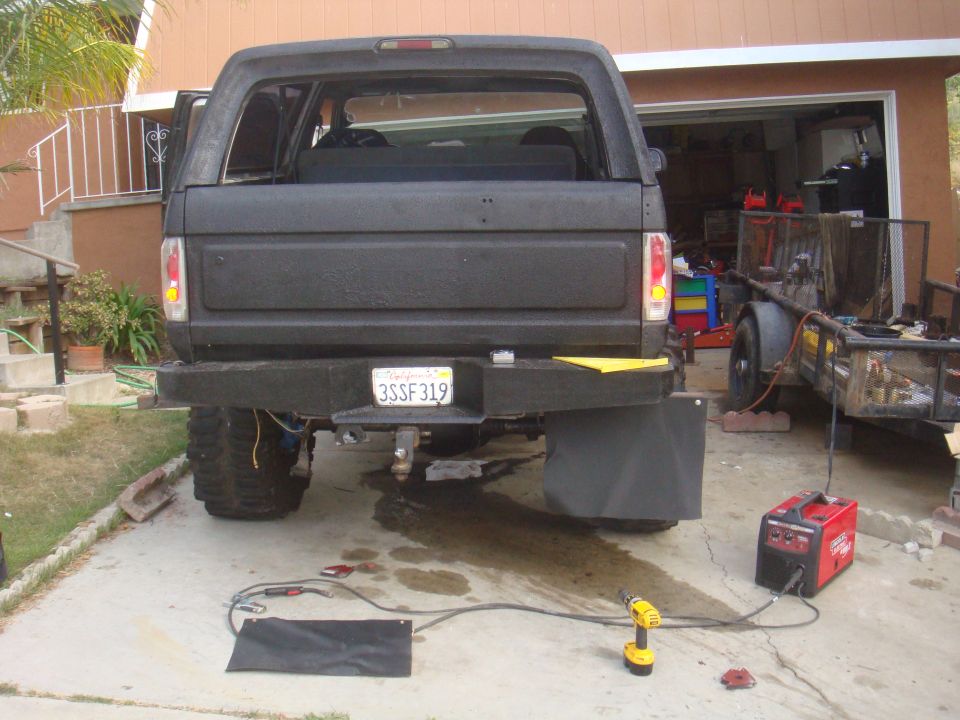 1992 Ford Bronco rear view with custom bumper and hitch. Trailer and welding equipment nearby