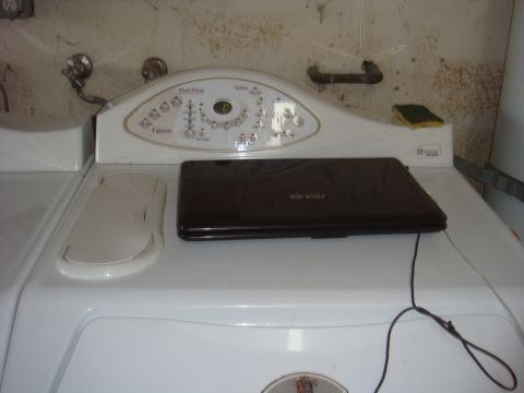 White washing machine control panel with a closed dark laptop on top