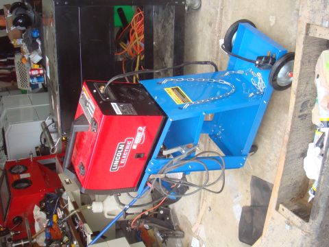 Red Lincoln Electric welder on a blue cart with wheels