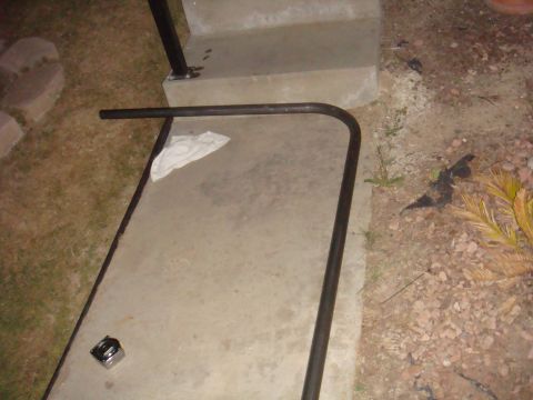Black metal bar with a curved end on concrete near steps