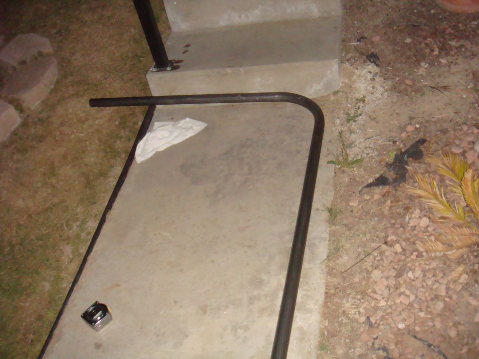 Black metal bar with a curved end on concrete near steps