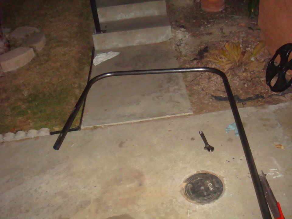 Black metal roll cage section on concrete driveway near stairs