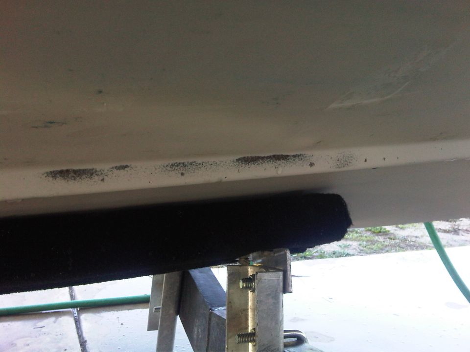 Close-up of a boat hull with a black fender and trailer supports