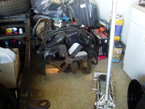 1986 Ford Bronco - Various engine components and automotive parts are organized in a storage area.
