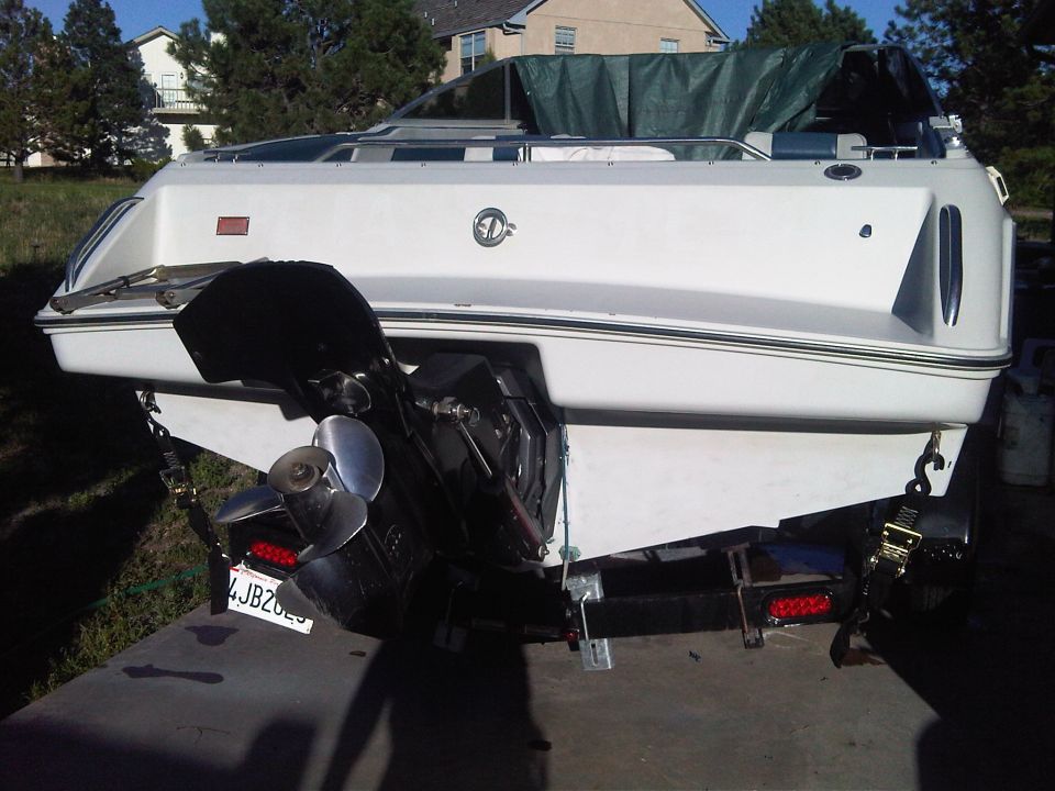 Stern of a white cabin cruiser on a trailer showing sterndrive and propeller