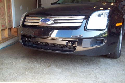 2006 Ford Fusion - Front view of a black 2006 Ford Fusion, showing the grille and a tow bar attachment point.