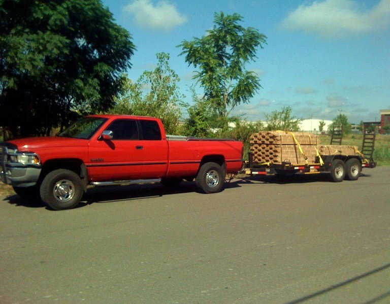 Red pickup truck, 1994 model year, towing a flatbed trailer loaded with bricks