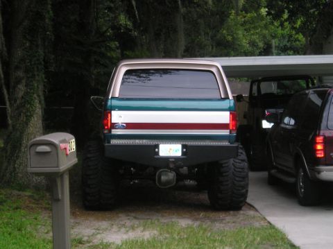 1978 Ford Bronco - This lifted Ford Bronco features a distinctive tri-color stripe on its rear panel and a custom aftermarket bumper.