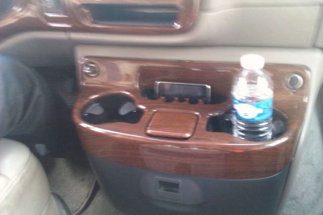 Interior console with wood trim, cup holders, and a water bottle