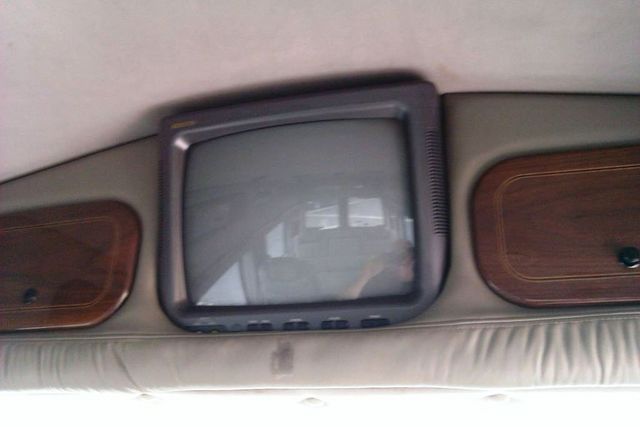 Van interior with a small TV mounted above wood-paneled cabinets