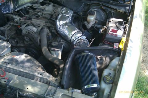 2000 Mercury Grand Marquis - The engine bay shows an aftermarket air filter and insulated intake hose, with the battery and brake fluid reservoir in view.