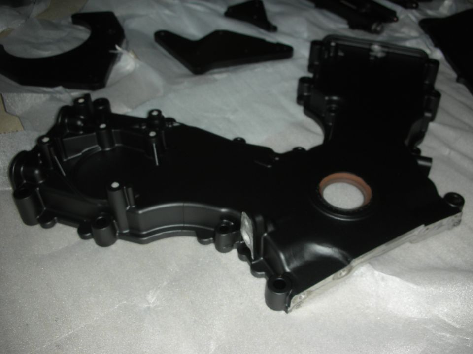 Black engine timing cover with a circular opening and mounting holes
