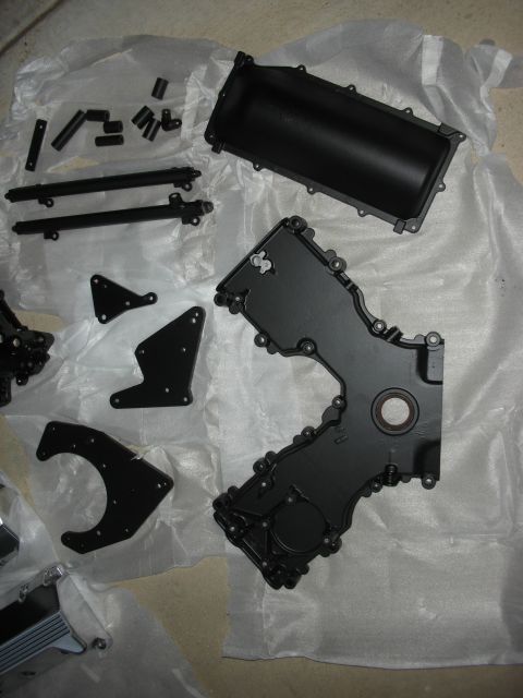 1992 Ford Crown Victoria - Various engine components, including a timing cover, are displayed on white paper, likely for a rebuild or upgrade project.