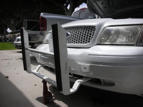 2004 Ford Crown Victoria - Low front three-quarter view of a white Ford Crown Victoria with the hood up and a white push bumper / ram bar with black rubber-faced upri…