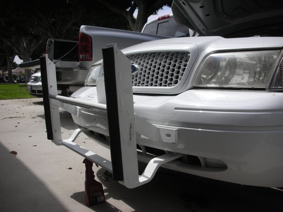 White push bumper being mounted to the front of a white Ford Crown Victoria