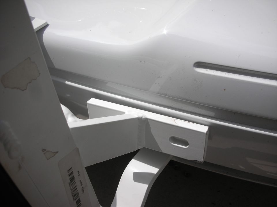 White-painted trailer hitch receiver bracket mounted under the rear bumper of a white sedan
