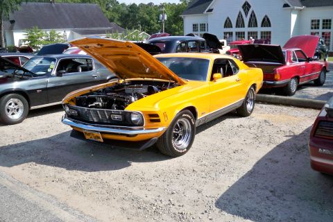 1980 Ford Mustang - A yellow 1970 Ford Mustang is displayed with its hood open at an outdoor car show.