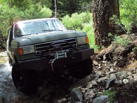 1989 Ford Bronco - This 1989 Ford Bronco is shown tackling a challenging off-road trail with water and rocks.