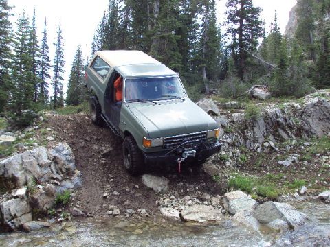 1989 Ford Bronco - This SUV navigates a challenging rocky terrain with a winch mounted on the front bumper.