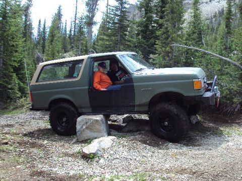 1989 Ford Bronco - 1989 Ford Bronco navigating rough terrain with two occupants.