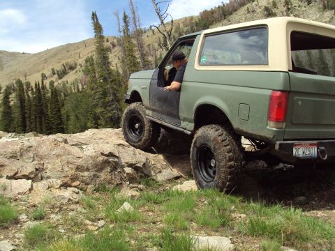 1989 Ford Bronco - A 1989 Ford Bronco navigates a rocky trail in a mountainous, wooded area.
