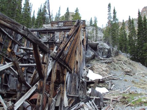 1989 Ford Bronco - An old, decaying wooden building stands on a steep, rocky slope surrounded by pine trees.