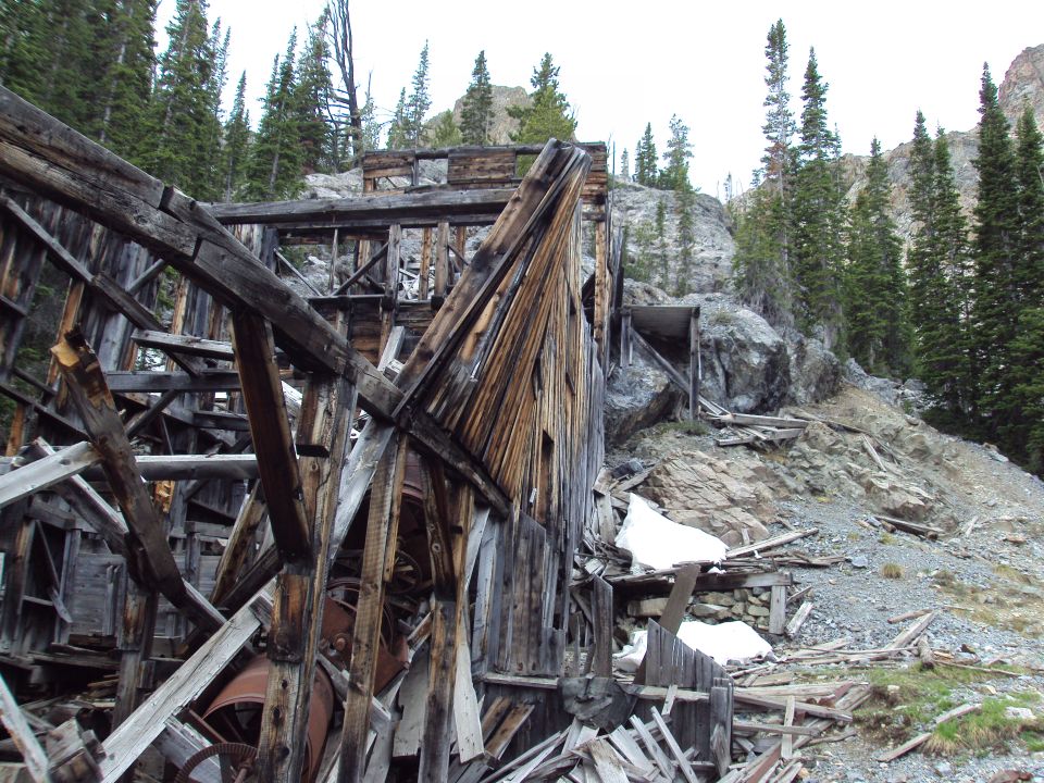 Dilapidated wooden mine structure on a rocky, forested mountainside