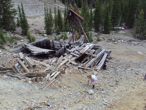 1989 Ford Bronco - A child investigates the remains of an old wooden structure amidst a rocky, forested mountainside.