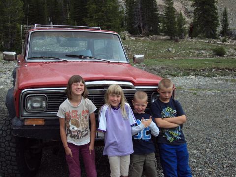1989 Ford Bronco - Children pose for a photo in front of a red SUV in a wooded, mountainous area.