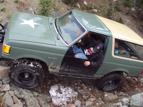 1989 Ford Bronco - A 1989 Ford Bronco is shown off-roading on a rocky trail with a driver inside.