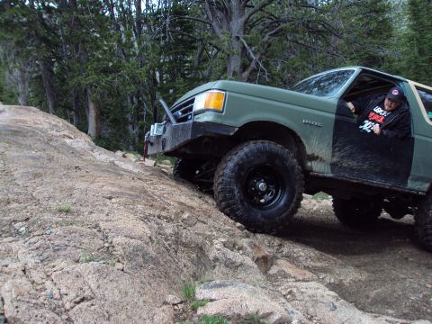 1989 Ford Bronco - This Ford Bronco navigates a challenging rocky trail in a wooded area.