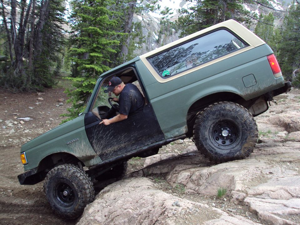1989 Ford Bronco navigating rocky terrain with driver visible