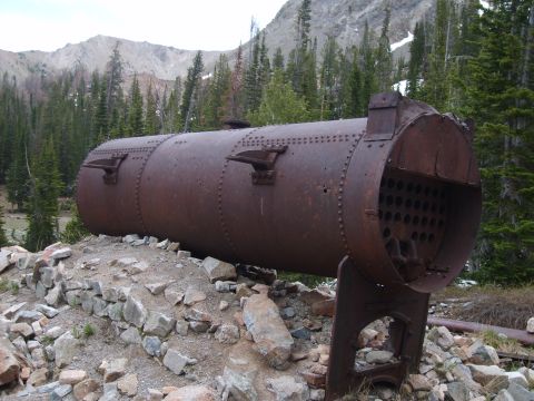 1989 Ford Bronco - An old, corroded boiler sits abandoned on a mountainside, surrounded by rocks and sparse vegetation.