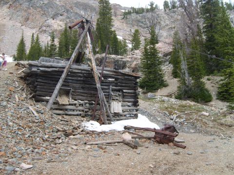 1989 Ford Bronco - An old, weathered mine structure sits in a rocky, mountainous landscape with scattered snow patches.
