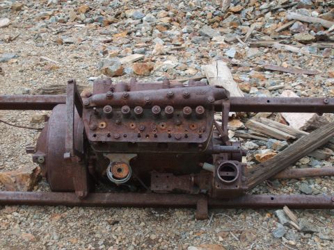 1989 Ford Bronco - A heavily rusted engine and chassis sit abandoned on a rocky terrain, with a watermark visible at the bottom right.