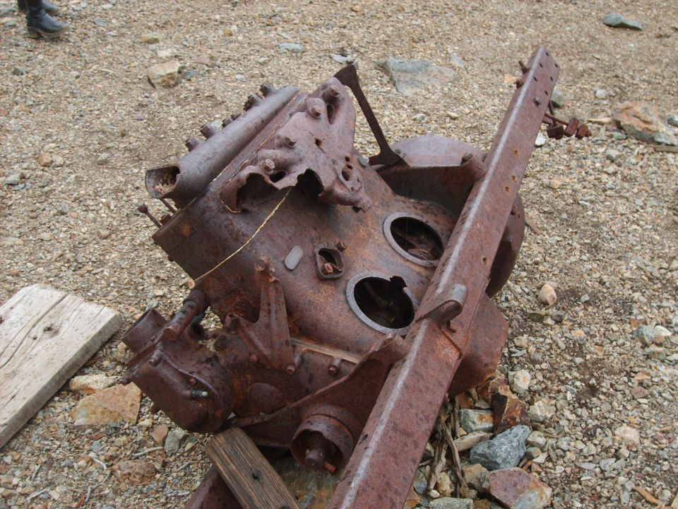 Rusted engine block and frame lying on gravelly ground