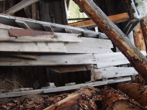 1989 Ford Bronco - A close-up view of a decaying wooden structure, revealing weathered planks and fallen logs.