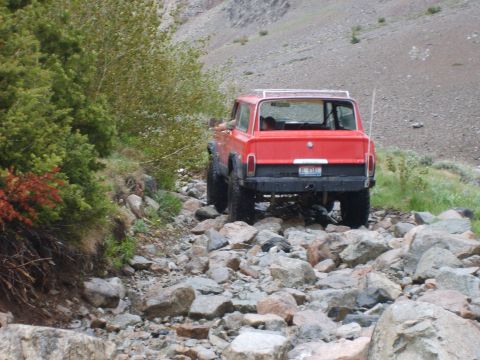 1989 Ford Bronco - Off-road vehicle tackles a difficult rocky trail in a mountainous landscape.