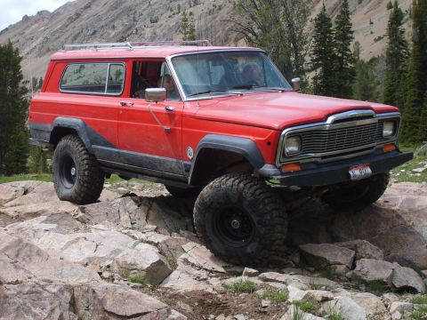 1989 Ford Bronco - This red 1984 Jeep Cherokee Chief navigates a rocky trail with large off-road tires.