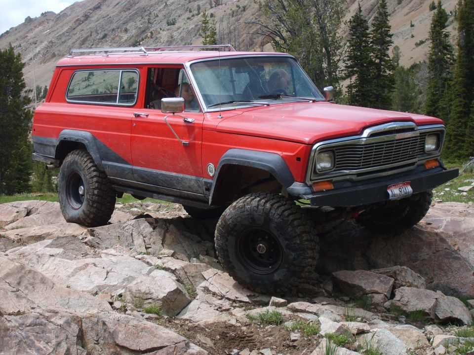Red 1984 Jeep Cherokee Chief off-roading on rocks