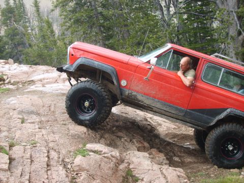 1989 Ford Bronco - A red Jeep Cherokee XJ navigates a challenging rocky trail, its off-road capabilities.