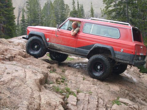 1989 Ford Bronco - Jeep Cherokee Chief navigates a challenging rocky trail in a mountainous area.