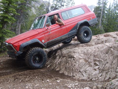 1989 Ford Bronco - This red SUV navigates a challenging rocky terrain, its off-road capabilities.