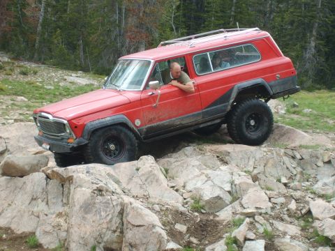 1989 Ford Bronco - This Jeep Cherokee Chief is tackling a challenging rocky trail in a wooded area.