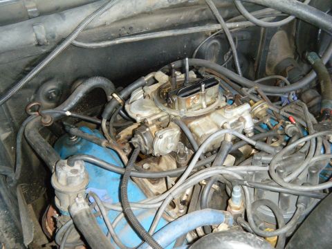 1985 Ford Bronco - Close-up view of a vehicle's engine bay, a carburetor and blue valve covers.