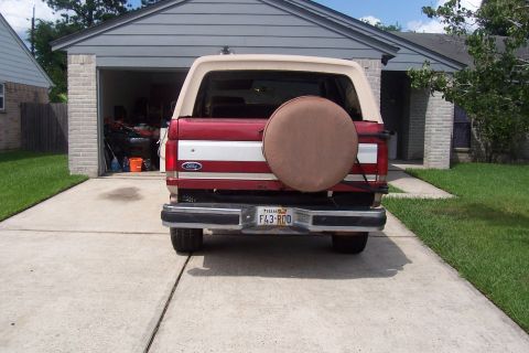 1988 Ford Bronco - Rear view of a red and tan 1988 Ford Bronco parked in a driveway.