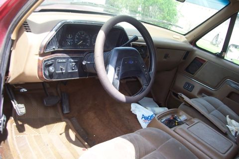 1988 Ford Bronco - The interior of a Ford Bronco, a tan dashboard and seats, with visible wear and tear.