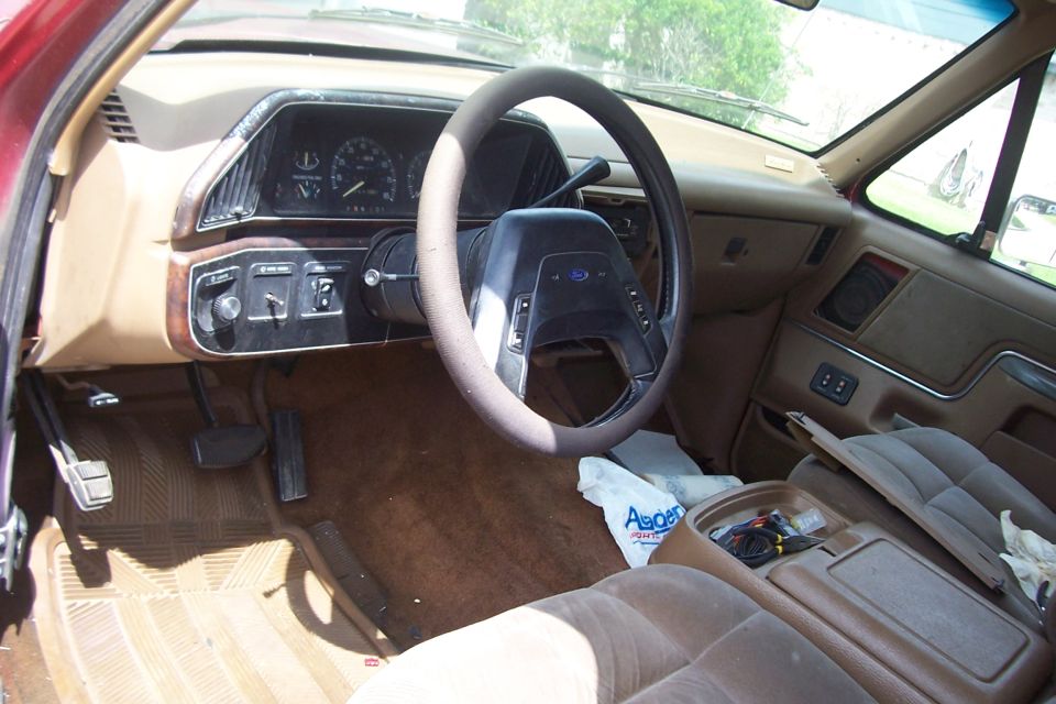 Interior of a red Ford Bronco with tan upholstery, showing the dashboard, steering wheel, and center console
